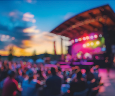 Blurred background of vibrant atmosphere of a summer concert held in an outdoor arena, featuring a lively audience cheering as the sun sets, creating a memorable experience.
