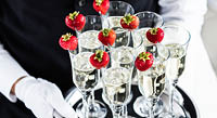 Waiter Standing With Champagne Glasses Next To Arranged Wedding Table