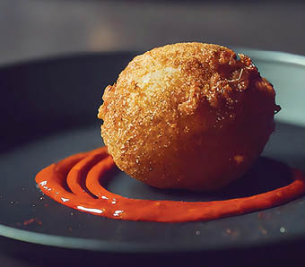 Cyberpunk photo of single round conch fritter with hot sauce on plate 