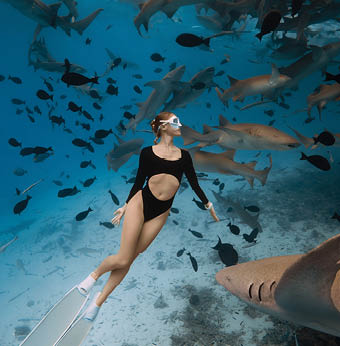 Slim woman freediver in a clear tropical water with nurse sharks in Maldives