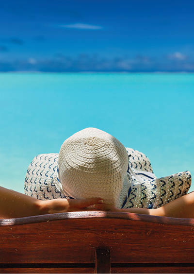 girl lays on a chaise lounge in the back on the banks of the turquoise Caribbean sea on Bahamian Maldivian Hawaiian beaches