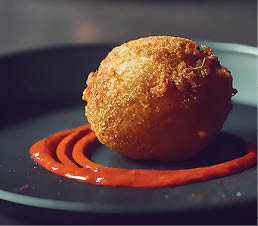 Cyberpunk photo of single round conch fritter with hot sauce on plate 