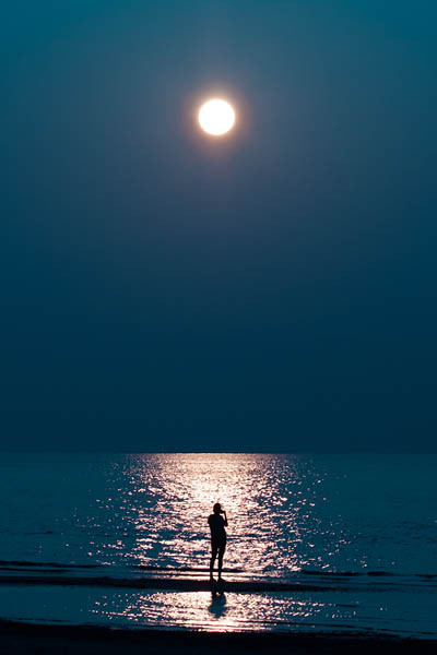 Someone is talking on the phone. the moon in the sky. moonlit road to the sea