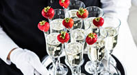 Waiter Standing With Champagne Glasses Next To Arranged Wedding Table