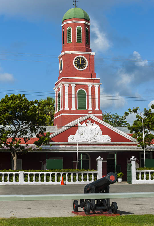Famous red clock tower on the main guardhouse at the Garrison Savannah with old cannons in front of it. UNESCO garrison historic area Bridgetown, Barbados