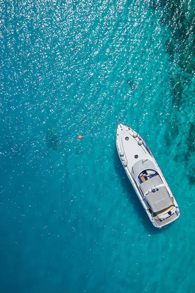 Luxury small yacht anchoring in shallow water, aerial view. Active life style, water transportation and marine sport.