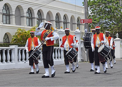 Bridgetown, Saint Michael, Barbados. March 22, 2018. Changing of the guard outside historic garrison. Sargeant major gives salute with drummers in background. Arches of former British garrison visible