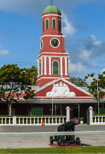 Famous red clock tower on the main guardhouse at the Garrison Savannah with old cannons in front of it. UNESCO garrison historic area Bridgetown, Barbados