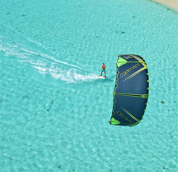 Aerial view young man kitesurfing in tropical blue ocean, extreme sport