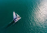 A catamaran moves through the teal waters of the Caribbean.