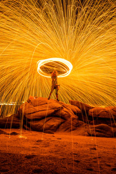 Fire dancer swing fire dancing show on the beach with dark sky background