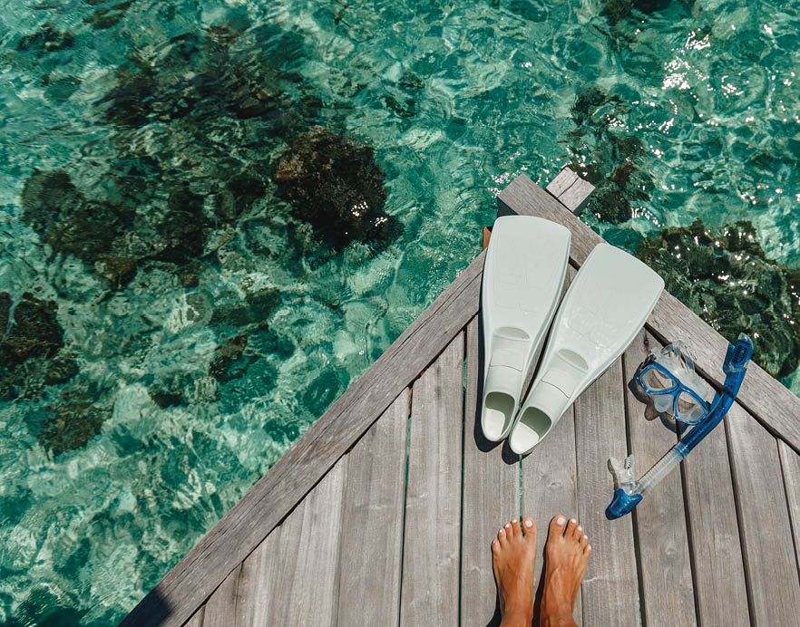 Beach vacation snorkel girl snorkeling with mask and fins. Equipment for snorkeling. Woman legs on wooden pier with snorkeling equipment