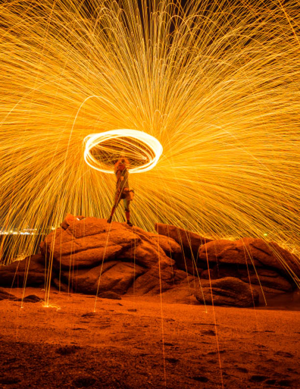 Fire dancer swing fire dancing show on the beach with dark sky background