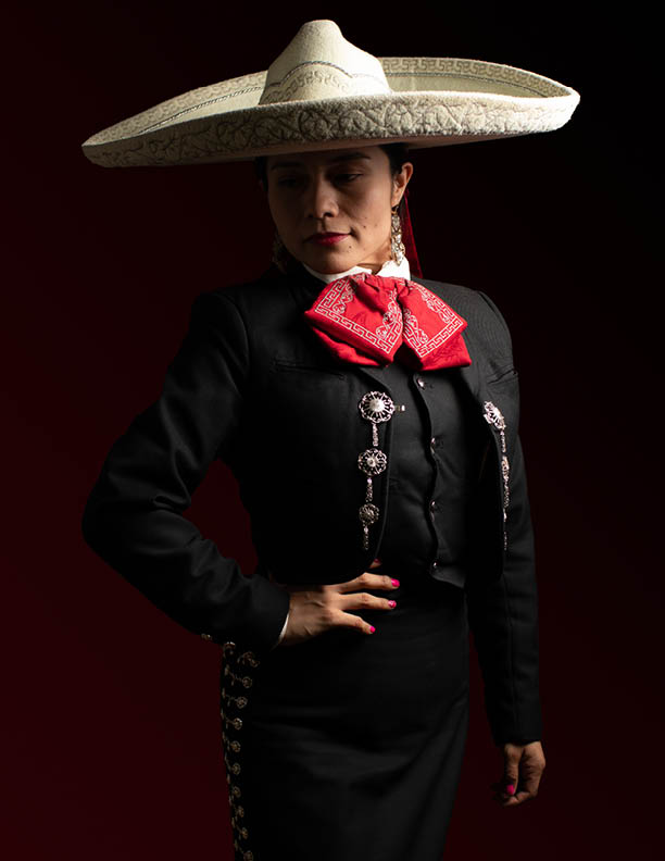 young good looking hispanic female mariachi mexican woman smiling, low key studio portrait