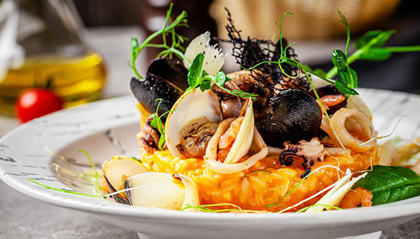 Italian food concept. Risotto with seafood, mussels, octopuses, squid. Serving dishes in a white plate. Modern serving in a restaurant. Background image. Copy space.