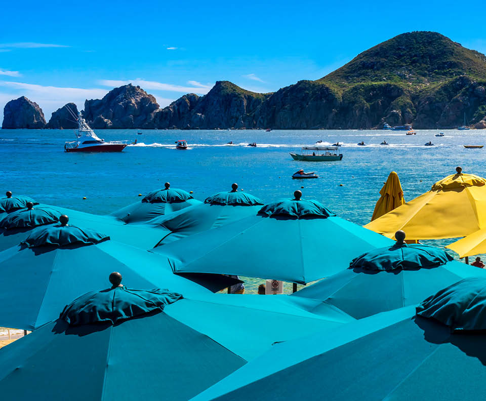 Blue Umbrellas Colorful Beach Restaurants Boats Water Taxi Swimmers Cabo San Lucas Baja Mexico. Los Cabos has many restaurants on sandy beaches.