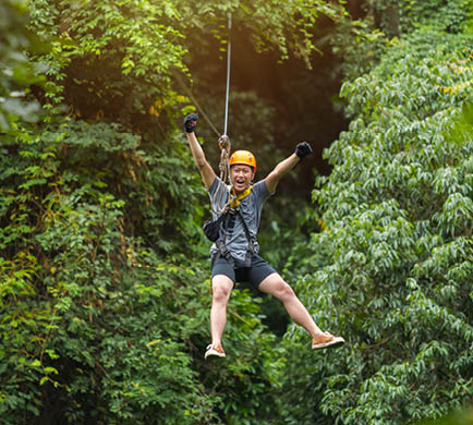Freedom Man Tourist Wearing Casual Clothing On Zip Line Or Canopy Experience In Laos Rainforest, Asia