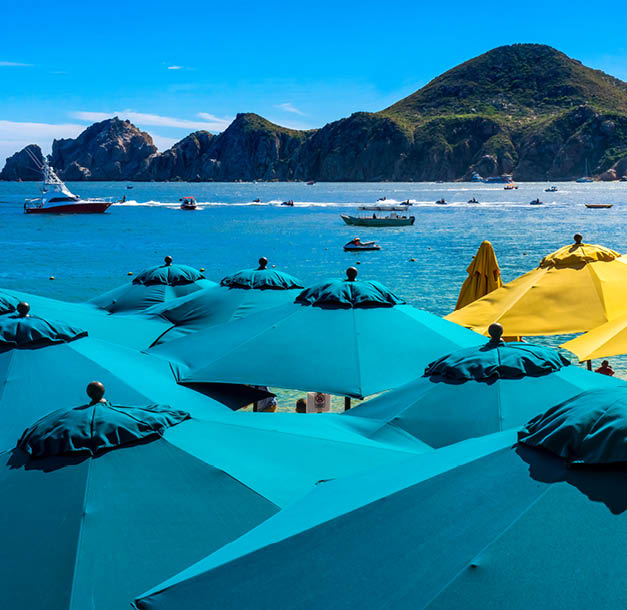Blue Umbrellas Colorful Beach Restaurants Boats Water Taxi Swimmers Cabo San Lucas Baja Mexico. Los Cabos has many restaurants on sandy beaches.