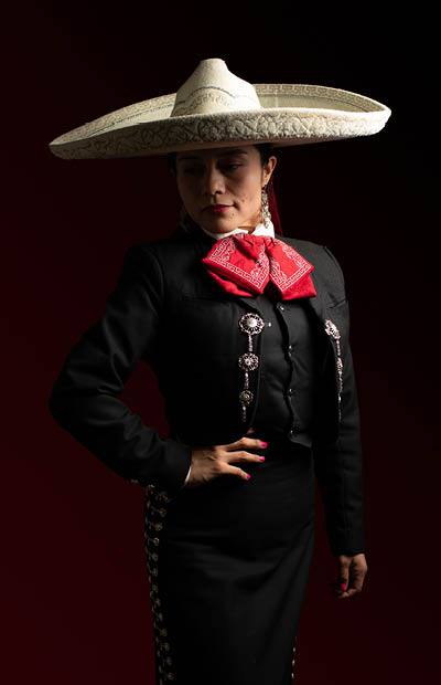 young good looking hispanic female mariachi mexican woman smiling, low key studio portrait