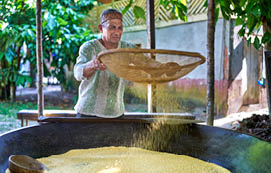 An indigenous man from the Amazon in the community flour house filtering the flour to remove impurities