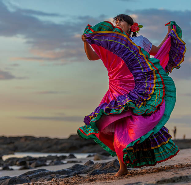 Costa Rican woman in traditional Guanacaste dress dancing in sunset light.