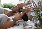 Hands, head massage and couple in spa to relax on bed for luxury pamper treatment together in hotel. Beauty, facial or zen woman with man at resort or salon for natural healing benefits or skincare