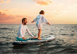 Surfing with sup board. Instructor teaches the pre-school girl to swim with a sup board. Sea and the sunset in the background. Summer vacations.
