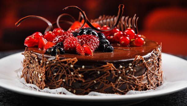 Luscious, tasty chocolate cake with fresh berries on a white plate. Close up brown delicious dessert with raspberry, black currant, red currant and blueberry. Dark, milk chocolate. Restaurant dish