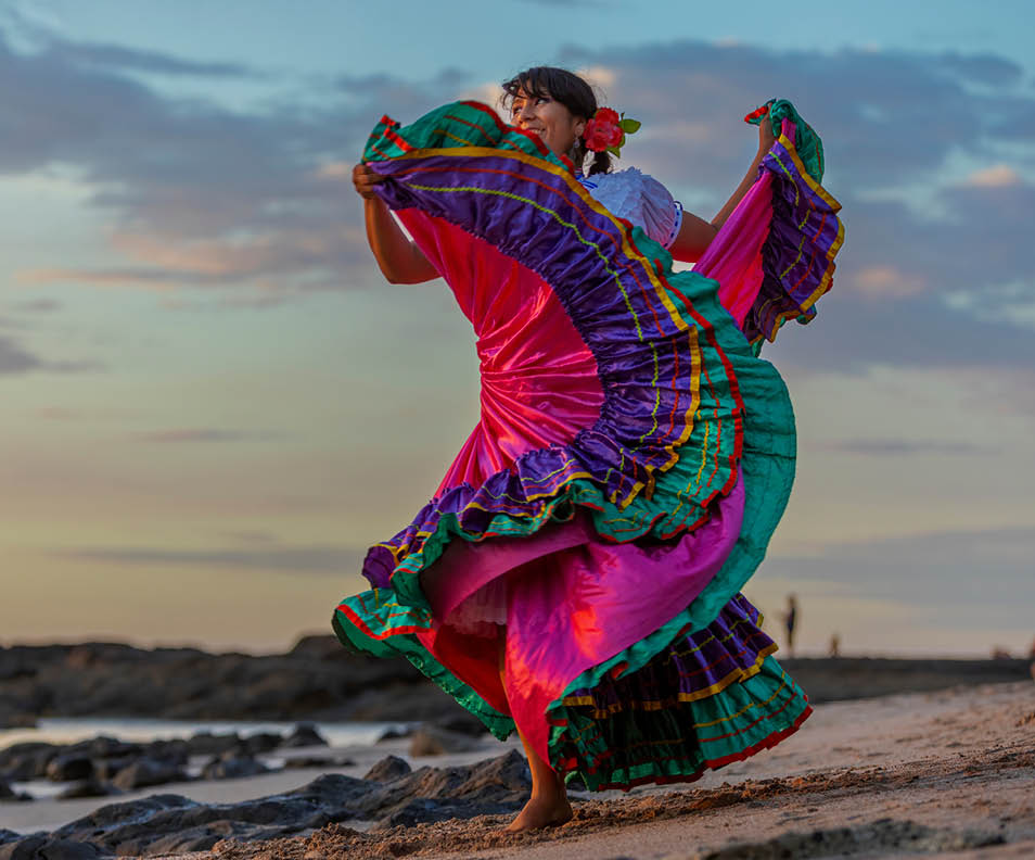 Costa Rican woman in traditional Guanacaste dress dancing in sunset light.