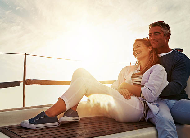 Hug, sunset and couple on a yacht for travel, retirement holiday and ocean adventure in Spain. Investment, hobby and man and woman on a boat for a luxury cruise, sailing and happiness at sea
