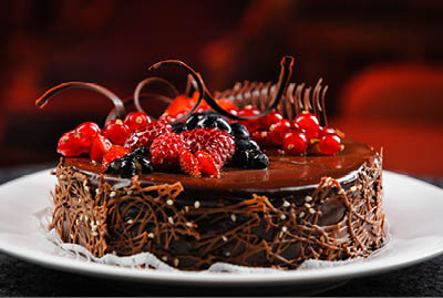 Luscious, tasty chocolate cake with fresh berries on a white plate. Close up brown delicious dessert with raspberry, black currant, red currant and blueberry. Dark, milk chocolate. Restaurant dish