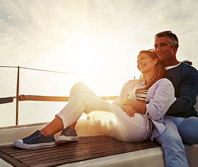Hug, sunset and couple on a yacht for travel, retirement holiday and ocean adventure in Spain. Investment, hobby and man and woman on a boat for a luxury cruise, sailing and happiness at sea