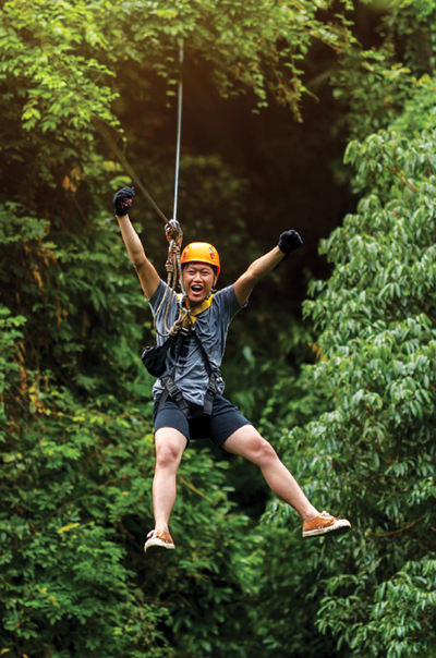 Freedom Man Tourist Wearing Casual Clothing On Zip Line Or Canopy Experience In Laos Rainforest, Asia