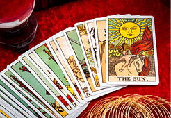 Fortune teller and whitcraft concept with tarot cards spread on red velvet surrounded by a magic crystal ball, gold bracelet, a book and a wooden box