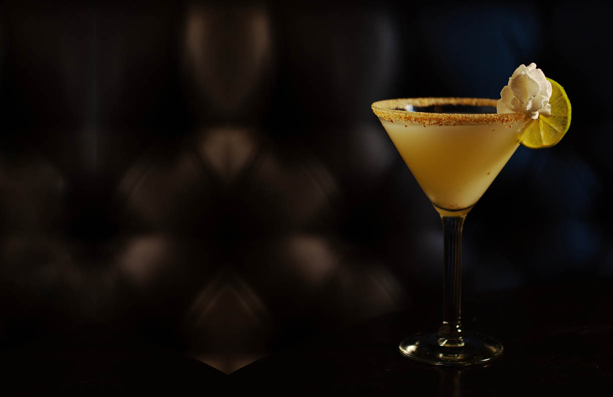 A key lime pie martini cocktail on a table dark background