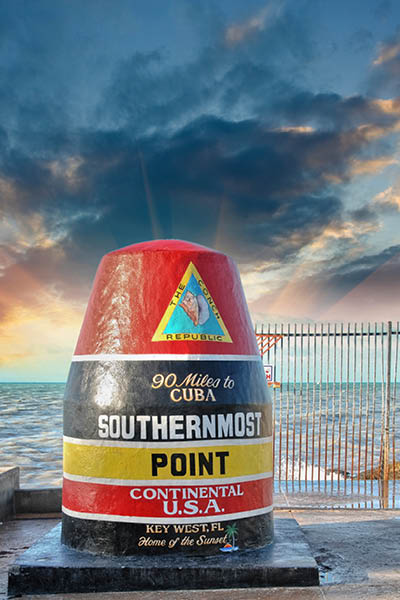 Southernmost Point sign in Key West, Florida. Beautiful seascape with sunset sky.