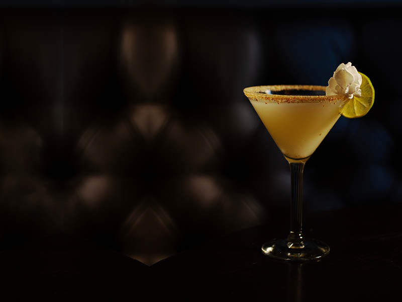 A key lime pie martini cocktail on a table dark background