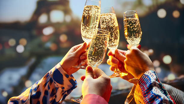 Bachelorette party. Close up shot of female hands holds glasses of sparkle wine in front of the main attraction in France. Travelling and relax. Concept of friendship, party, date, romantic, vacation.