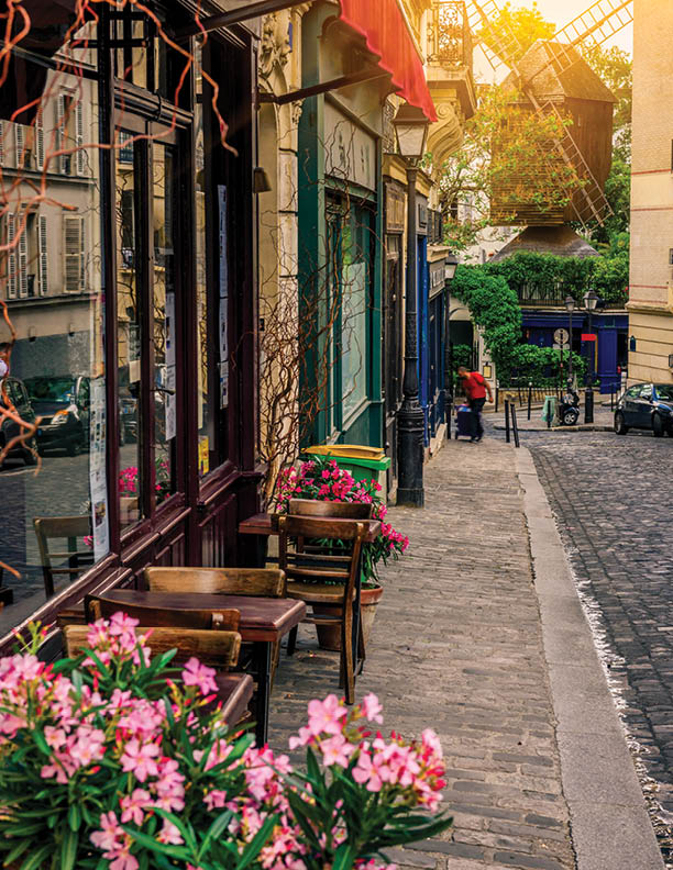Cozy street with tables of cafe and old mill in quarter Montmartre in Paris, France. Architecture and landmarks of Paris. Postcard of Paris