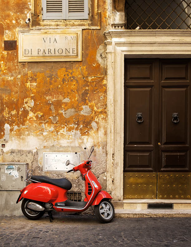 ROME,ITALY - JULY 17,2017 : Old narrow street in Rome with a typical red vespa scooter on a cobblestone street