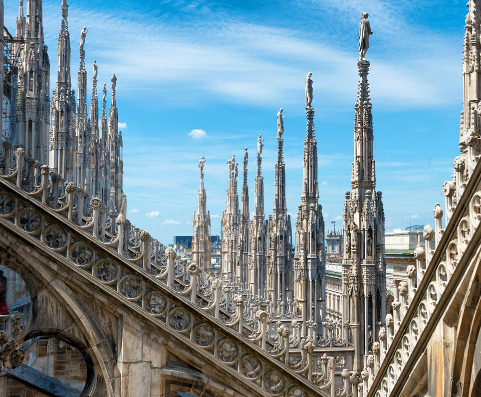 White marble statues on the roof of famous Cathedral Duomo di Milano on piazza in Milan, Italy 