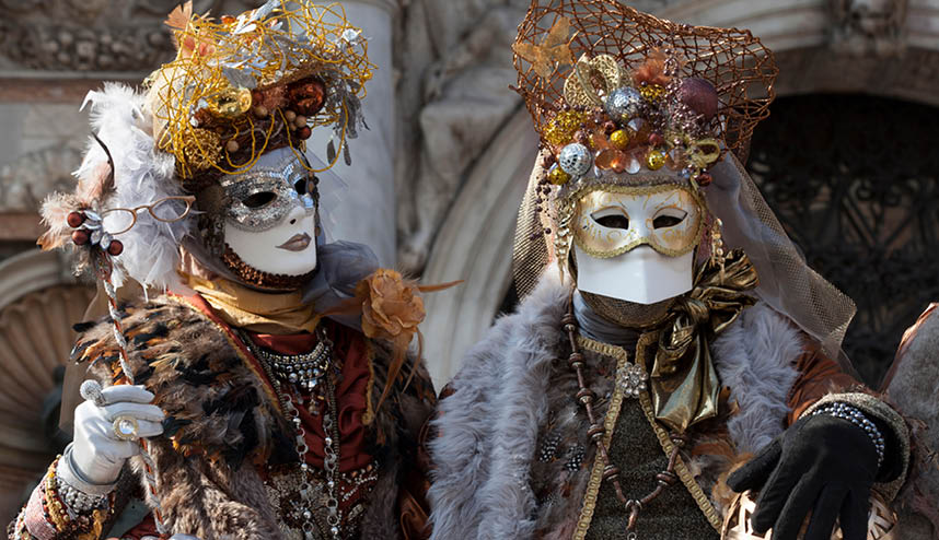 2 Venice Carnival Figures in a colorful gold and brown costumes and masks Venice Italy