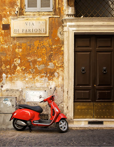 ROME,ITALY - JULY 17,2017 : Old narrow street in Rome with a typical red vespa scooter on a cobblestone street