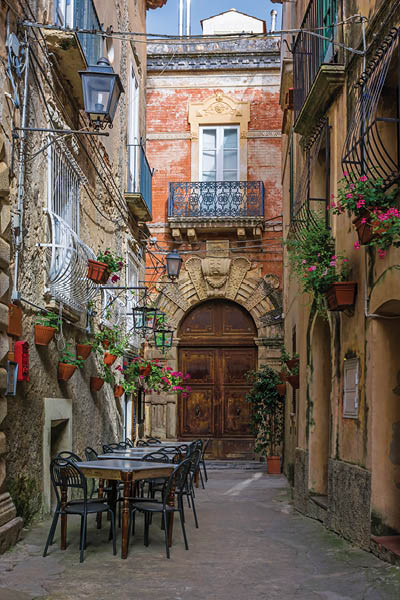 Cafe tables and chairs outside in old cozy street in the Positano town, Italy