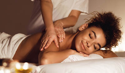 African-american girl enjoying relaxing back massage and aroma therapy in spa centre