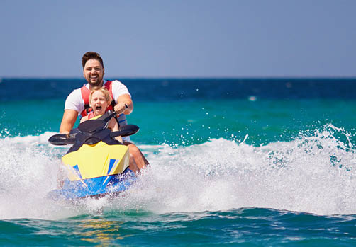happy, excited family, father and son having fun on jet ski at summer vacation