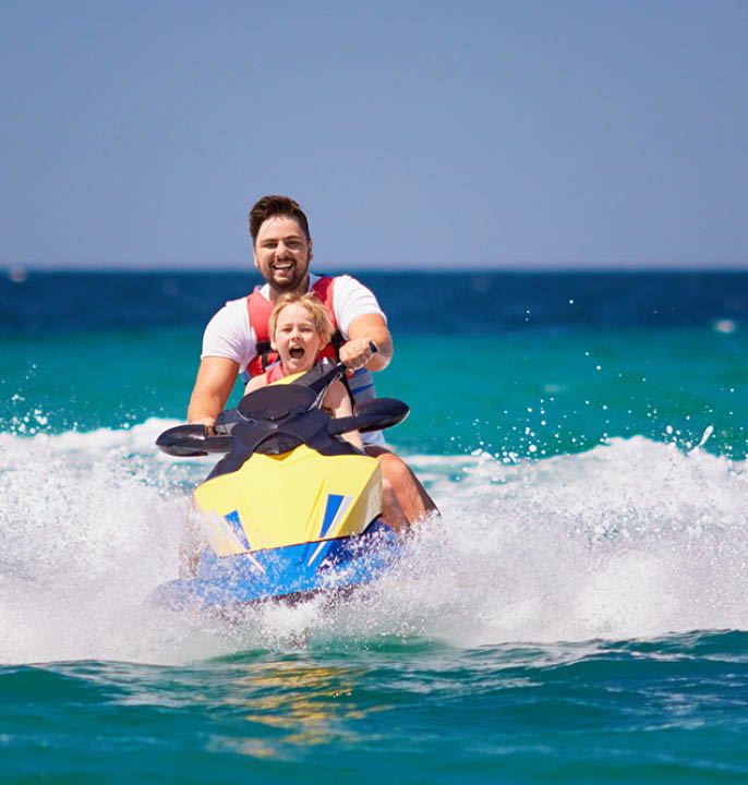 happy, excited family, father and son having fun on jet ski at summer vacation