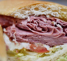 Bright close up of authentic New England style “grinder" Italian cold cut sandwich filled with meat cheese and lettuce and tomato.