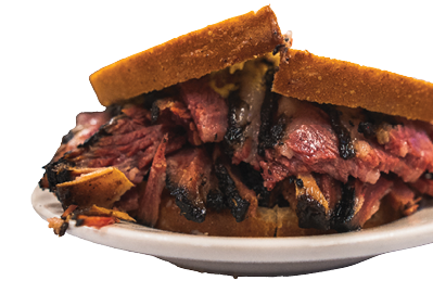 Famous thick cut pastrami sandwhich in New York City at a deli with great meet great cuts on rye bread with oils dripping at a diner while hand held and half cut for easy eating