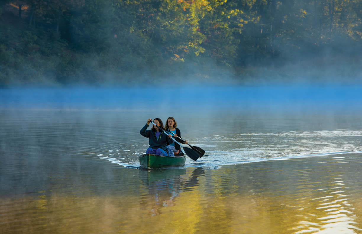 Mother and daughter canoeing in morning mist